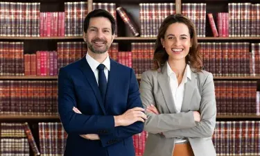 Legal Studies Graduates Smiling in Front of Bookshelves